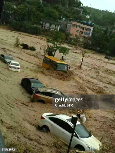 This image taken with a cameraphone shows cars and buses being washed away by floodwaters in Fuzhou, in eastern China's Fujian province on July 9,...