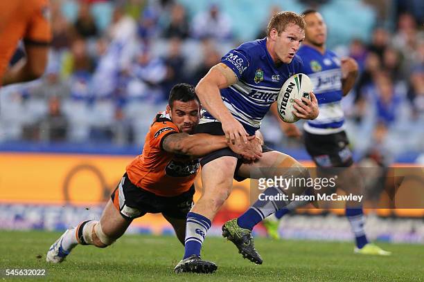Aiden Tolman of the Bulldogs is tackled by Dene Halatau of the Tigers during the round 18 NRL match between the Canterbury Bulldogs and the Wests...