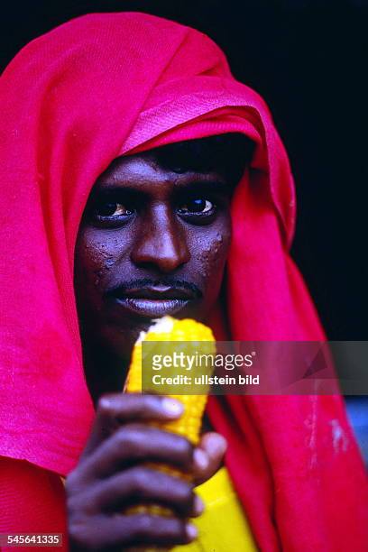 Mann mit rotem Tuch isst Maiskolben- 1998