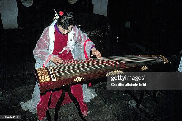 Musikerin spielt auf einem traditionellenSaiteninstrument- 1994