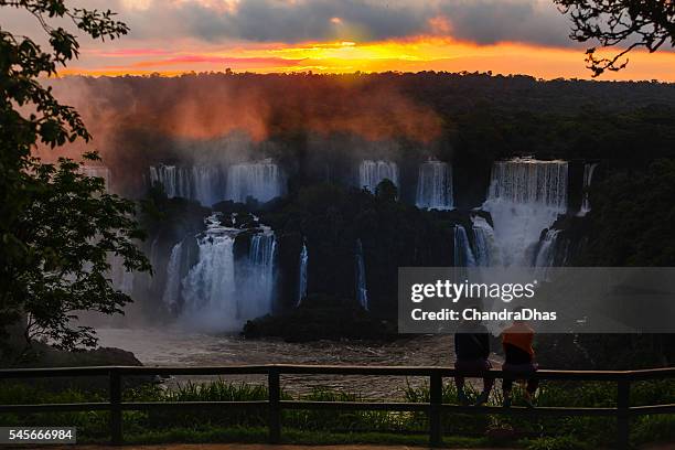 iguazú, brasil: silueta de turistas en las famosas cataratas, viendo una dramática puesta de sol sobre las cataratas cerca de la garganta del diablo - garganta del diablo fotografías e imágenes de stock