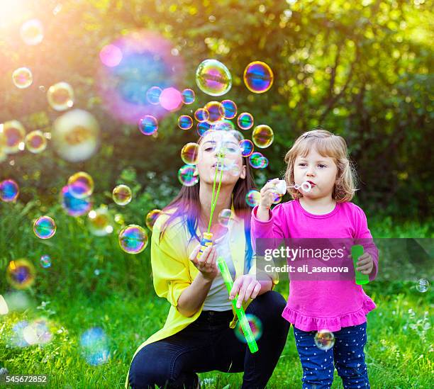 happy mother and her child playing with soap bubbles - bubbles happy stockfoto's en -beelden