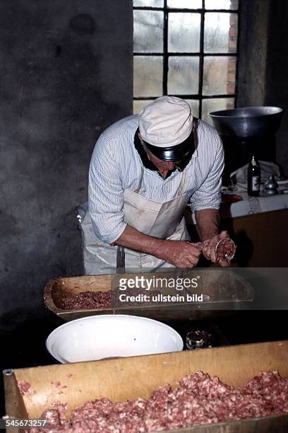 Schlachter bei der Herstellung vonWurst aus Schweinefleisch: füllt dieWurstmasse in Därme- in der Altmark Februar 1999 !