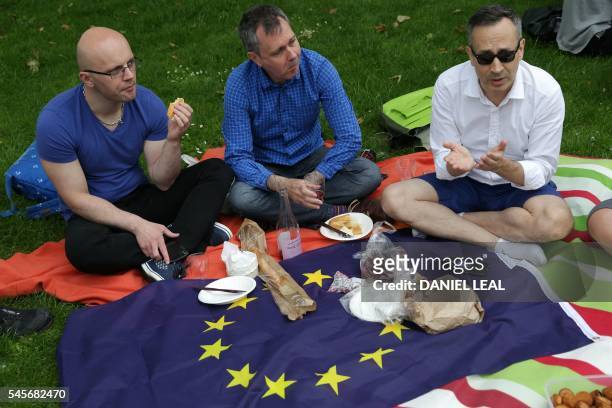 People use a European Union flag as a blanket while taking part during a picnic against Brexit organised by the General Assembly in Green Park in...