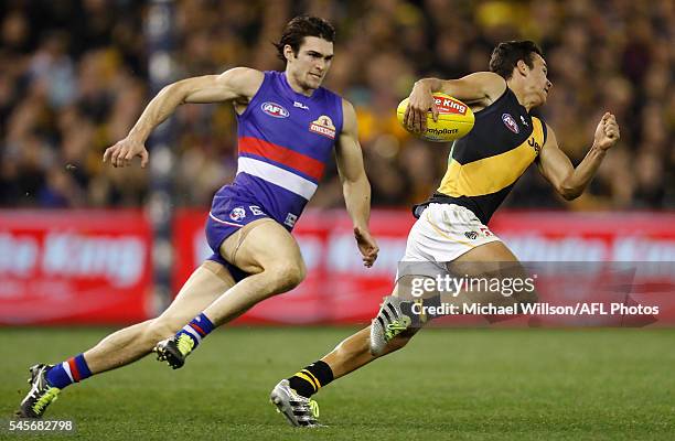 Daniel Rioli of the Tigers is chased by Easton Wood of the Bulldogs during the 2016 AFL Round 16 match between the Western Bulldogs and the Richmond...