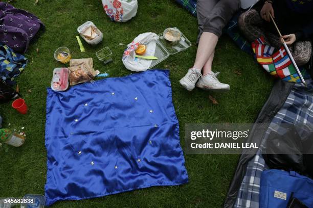 People use a European Union flag as a blanket while taking part during a picnic against Brexit organised by the General Assembly in Green Park in...