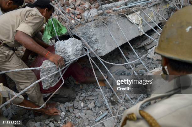 Indian police and volunteers try to pull a body from the rubble of a collapsed building in the northern city of Meerut on July 9, 2016. Four people...