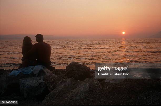 Paar sitzt bei Sonnenuntergang am Strand von Brela / Dalmatien / Kroatien- August 2001