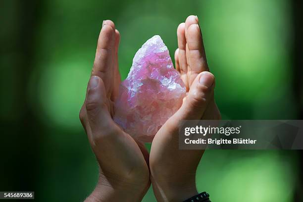 hands holding a rose quartz - kristallheilung stock-fotos und bilder