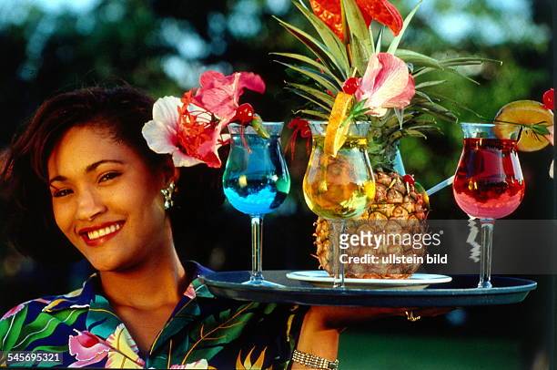 Karibik: Frau hält ein Tablett mitexotischen, bunten Drinks, garniert mitverschiedenen Früchten- 1996 col
