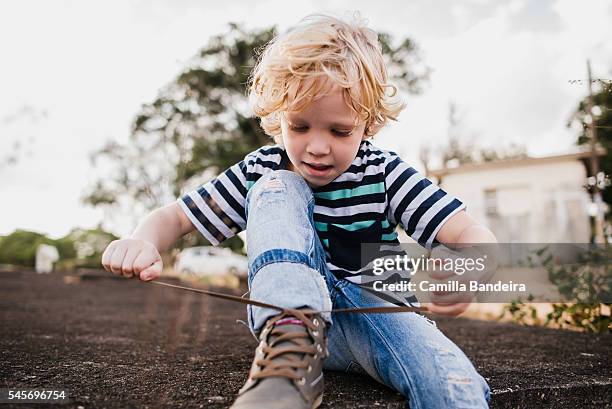 boy learning to tie his shoelaces - stringa foto e immagini stock