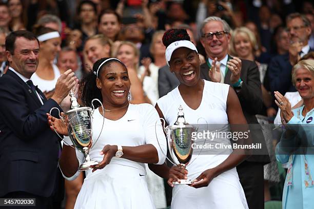 Venus Williams of The United States and Serena Williams of The United States hold up their trophies following victory in the Ladies Doubles Final...