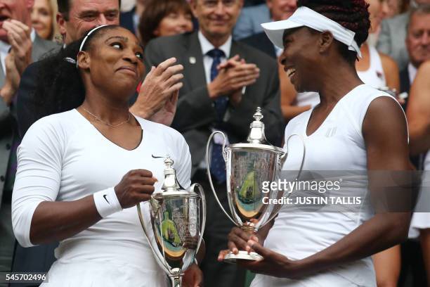 Player Serena Williams and her partner US player Venus Williams pose with the winner's trophies after beating Hungary's Timea Babos and Kazakhstan's...