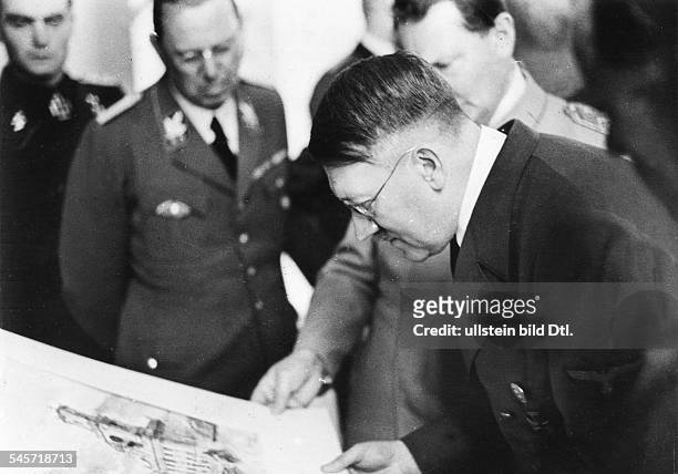 Hitler mit Brille betrachtet ein geschenktes Aquarell; im Hintergrund: Hermann Göring und der persönliche Adjutant SS-Führer Julius Schaub