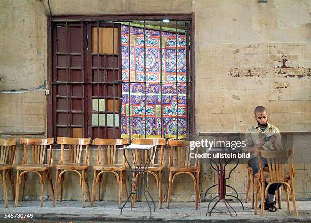 Egypt Cairo Cairo - Ramadan, young man is reading the Koran in front of a tea room before breaking the fast in the evening