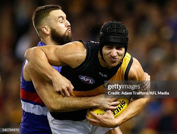 Ben Griffiths of the Tigers is tackled by Matthew Suckling of the Bulldogs during the 2016 AFL Round 16 match between the Western Bulldogs and the...