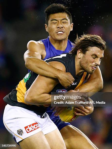 Sam Lloyd of the Tigers is tackled by Lin Jong of the Bulldogs during the 2016 AFL Round 16 match between the Western Bulldogs and the Richmond...