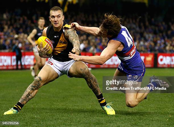 Dustin Martin of the Tigers fends off Liam Picken of the Bulldogs during the 2016 AFL Round 16 match between the Western Bulldogs and the Richmond...