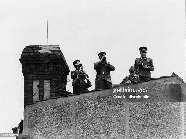 Angehörige der DDR-Grenztruppenbeobachten am Potsdamer Platz denKonvoi der Königin