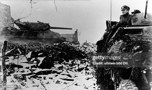 Battle of the Bulge, December 1944: Armored half tracked vehicles on the advance. On the left: a destroyed US Tank -