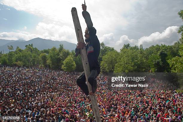 Kashmiri Muslim clims a pole to have a glimpse of Burhan Wan a top Hizb ul Mujahideen commander killed in a brief gun battle with Indian government...