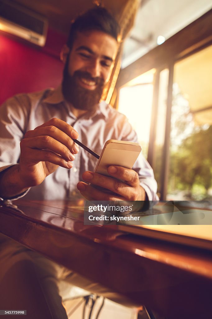 Close-up of businessman using stylus on smart phone.