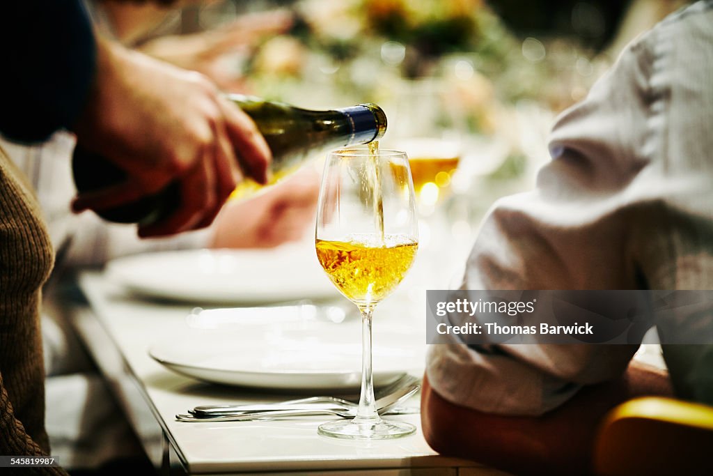 Server pouring glass of wine during dinner