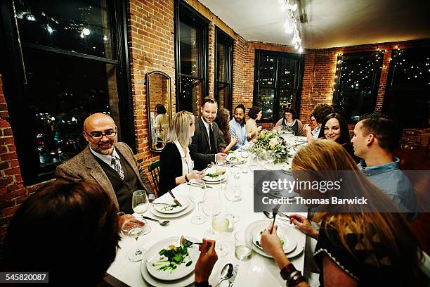 smiling friends dining together at dinner party - reglas de sociedad fotografías e imágenes de stock