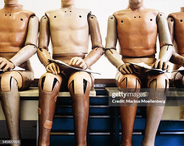 dummies sitting in row on bench - crash test dummies stock-fotos und bilder