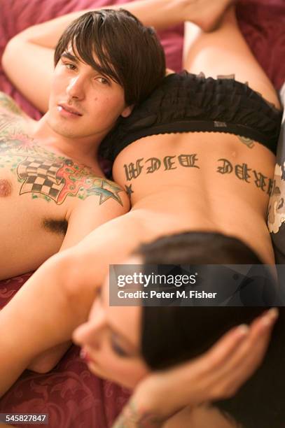 tattooed couple lying on bed - intimpiercing stock-fotos und bilder