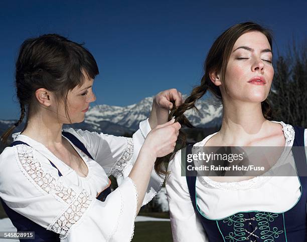 woman braiding friends hair - dirndl stock pictures, royalty-free photos & images