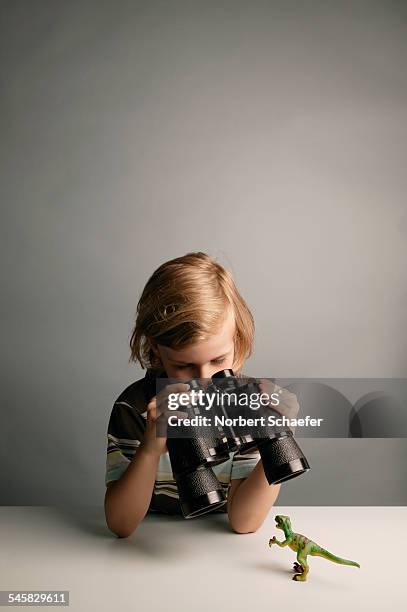 boy examining toy dinosaur with binoculars - dinosaur toy i stock pictures, royalty-free photos & images