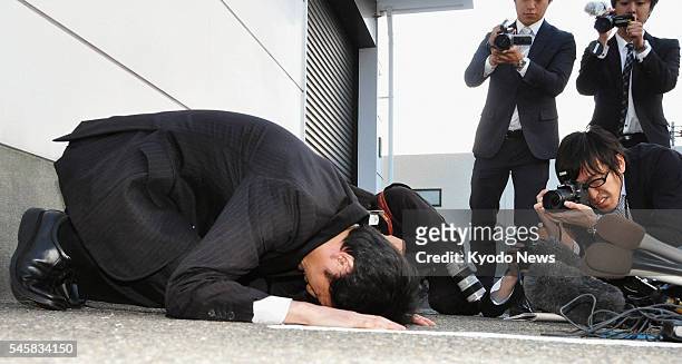 Japan - Yasuhiro Kanzaka , president of Foods Forus Co., prostrates himself in apology in front of the company's head office in Kanazawa, Ishikawa...