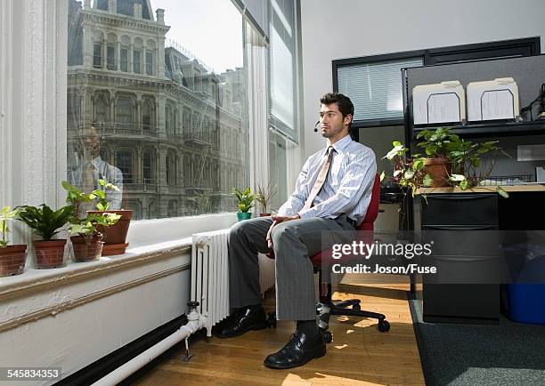 businessman with headset staring out the window - plante verte bureau photos et images de collection