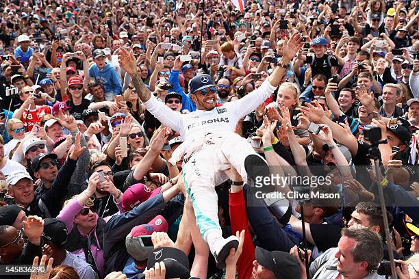Lewis Hamilton of Great Britain and Mercedes GP crowd surfs with the fans to celebrate his win during the Formula One Grand Prix of Great Britain at...