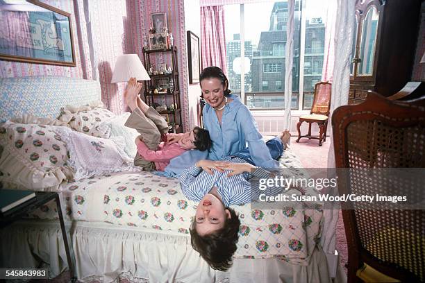 Swiss-born socialite Gloria Vanderbilt poses with her two sons Anderson Cooper and Carter Vanderbilt Cooper on her bed in their apartment in the UN...