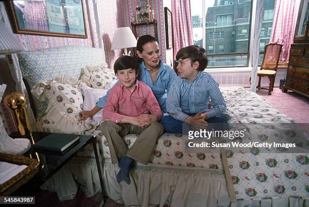 Swiss-born socialite Gloria Vanderbilt poses with her two sons Anderson Cooper and Carter Vanderbilt Cooper on her bed in their apartment in the UN...