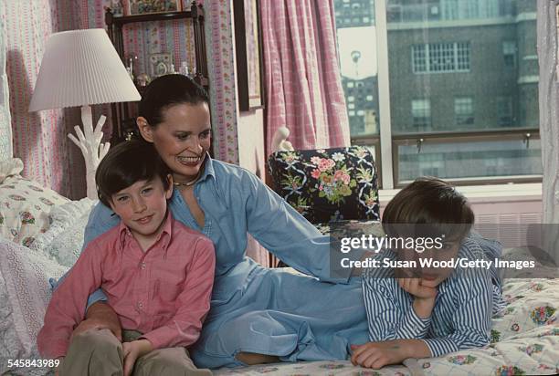 Swiss-born socialite Gloria Vanderbilt poses with her two sons Anderson Cooper and Carter Vanderbilt Cooper on her bed in their apartment in the UN...