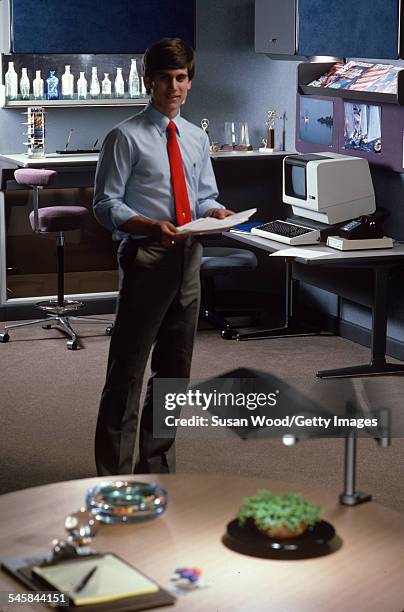 In a modular office, an unidentified man poses with a stack of paper, April 1984. The photo was taken as part of a shoot for the Herman Miller...
