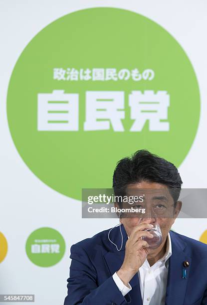 Shinzo Abe, Japan's prime minister and president of the Liberal Democratic Party , drinks a glass of water as he speaks to the media after the upper...