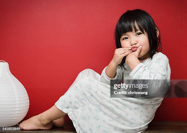 portrait of girl sitting against red wall, puckering lips - negligée stock-fotos und bilder