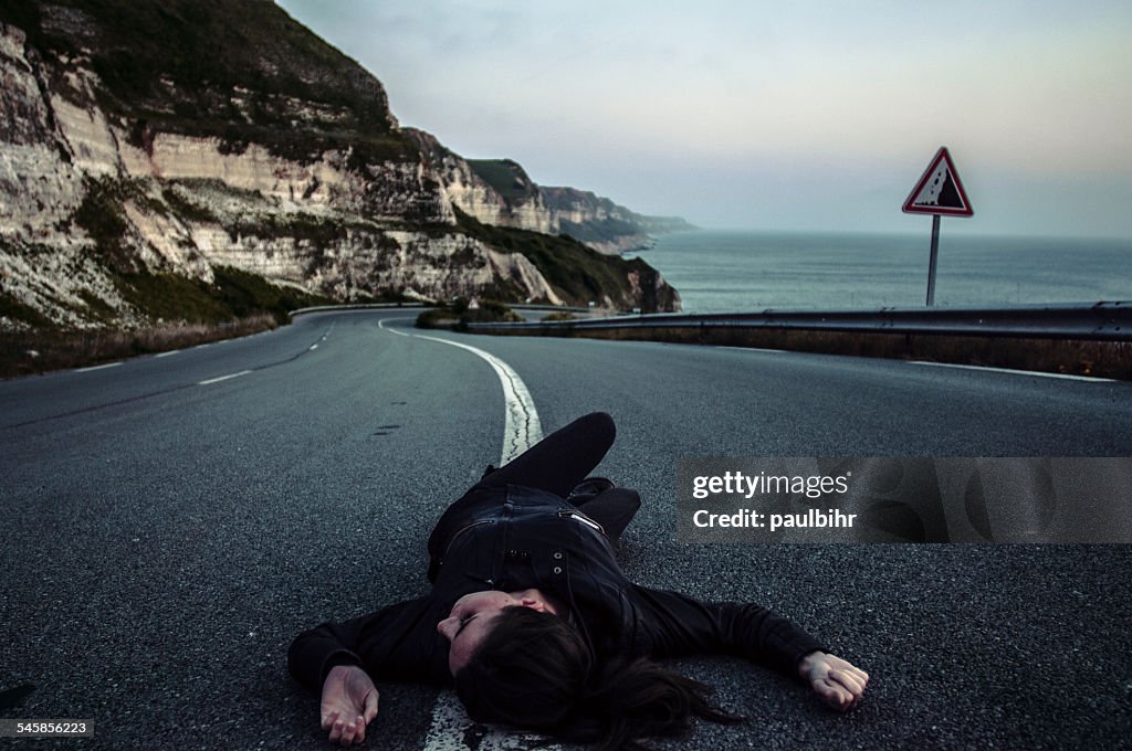 Woman lying down in middle of road
