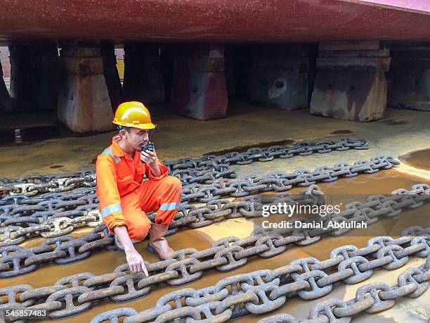 dock worker in a shipyard talking on a walkie talkie - shipbuilder stock pictures, royalty-free photos & images