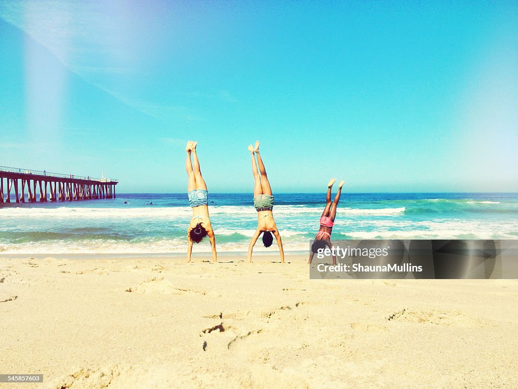 Mother, father and daughter doing handstand on beach