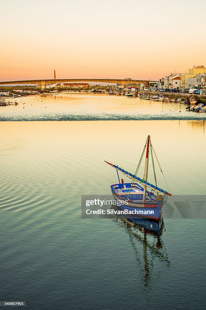 Portugal, Tavira, Fishing boat on river with town in background
