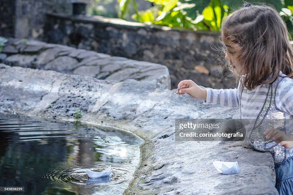 Girl sailing paper boats in fountain