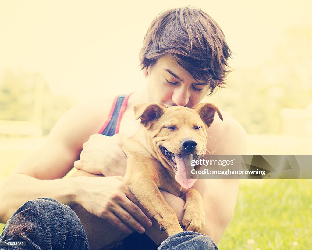 Young man holding puppy outdoors