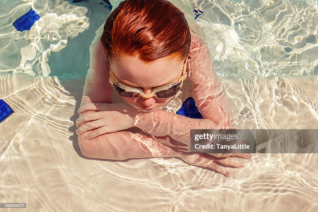 Boy in a swimming pool leaning on his arms