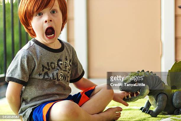 boy playing with toy dinosaur, pretending he's been bitten - dinosaur toy i - fotografias e filmes do acervo