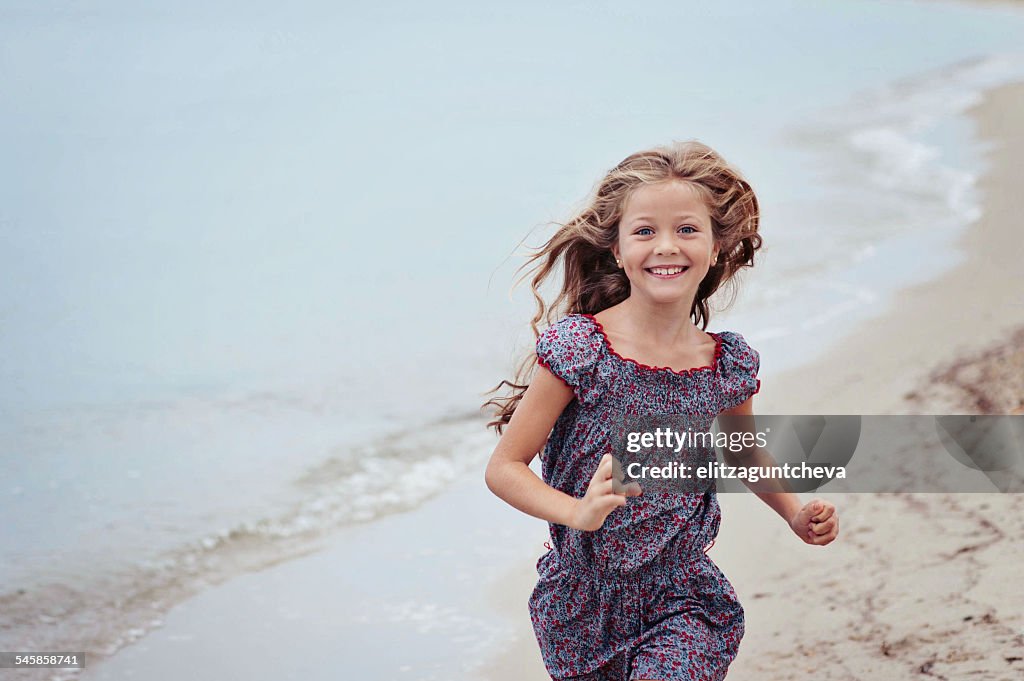 Beautiful girl (6-7) running on beach